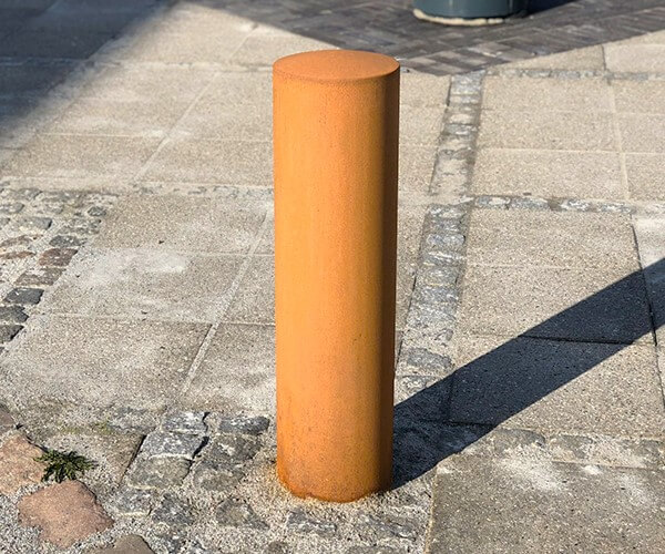rund corten pullert nedstøbt på gaden i midtbyen