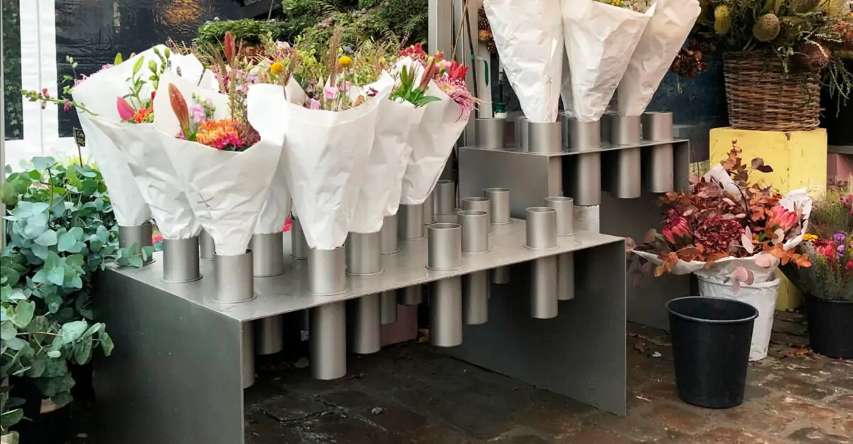 bord i rustfrit stål med mange holdere til krukker med blomsterstilke i butikken i København