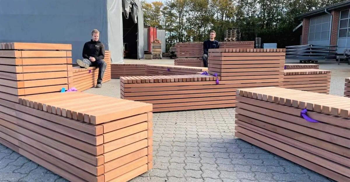en række bænke specielt designet til dette projekt, lavet af galvaniseret stål og beklædt med mahogniplanker står i gården af By Bangs værksted
