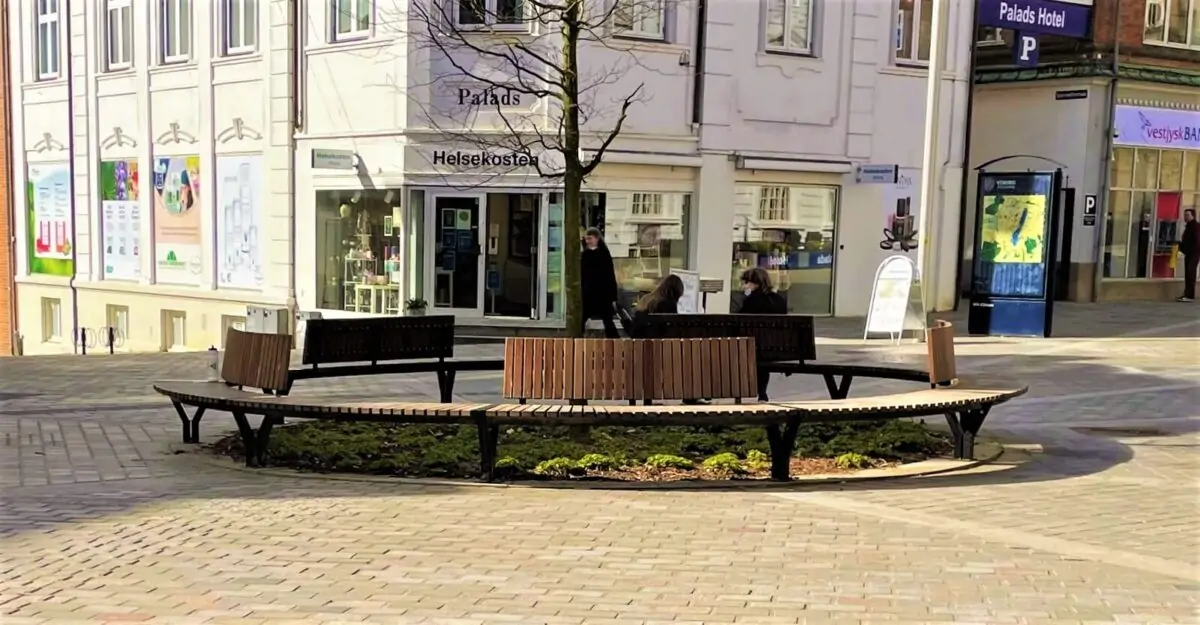 Cirkelbænk med ryglæn i malet stål og beklædt med lakerede mahogni stave i Viborg