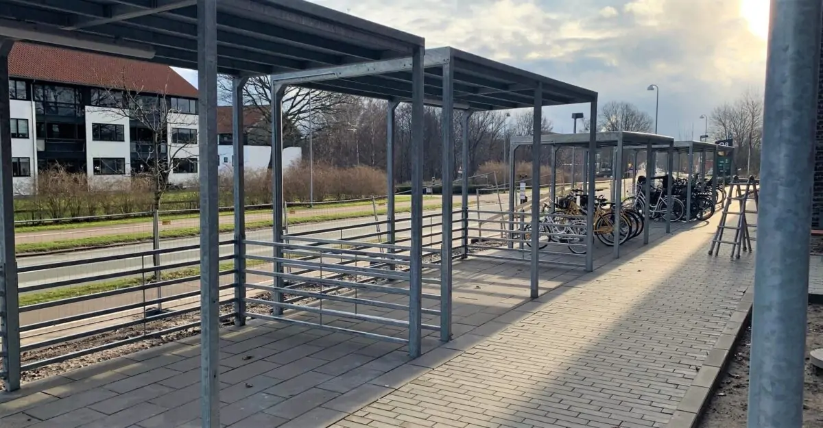 en stor enkel cykeloverdækning i galvaniseret stål med en række af cykelstativer til mange cykler og et sedum tag