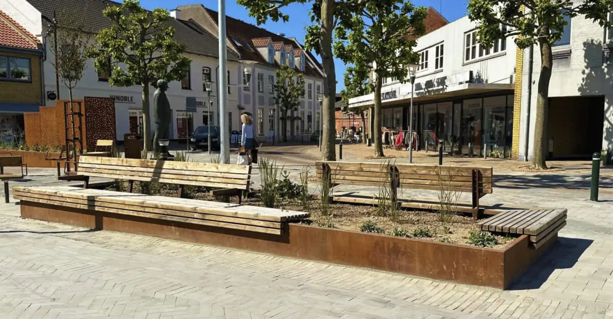 en cortenstål plantekasse med bænk beklædt med mahogni træ monteret på den