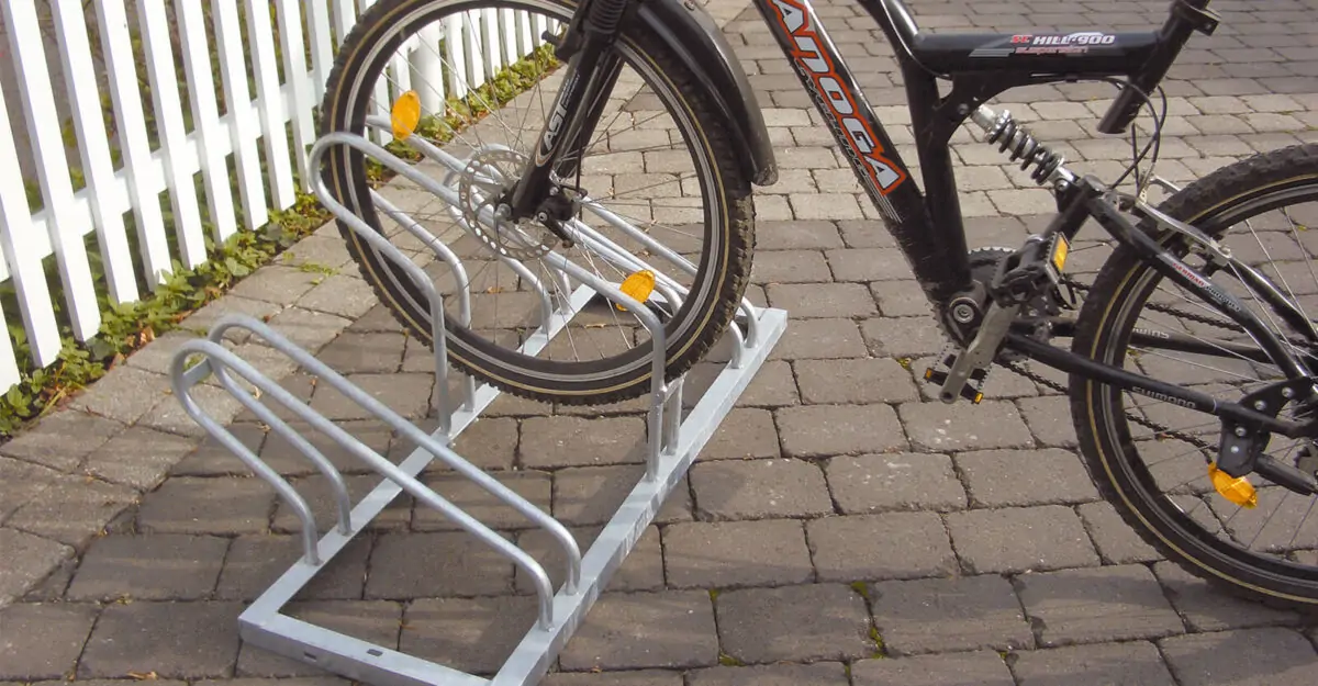 cykel parkeret i en pladsbesparende cykelholder i galvaniseret stål bestående af høje/lave cykelbøjler til parkering af mange cykler