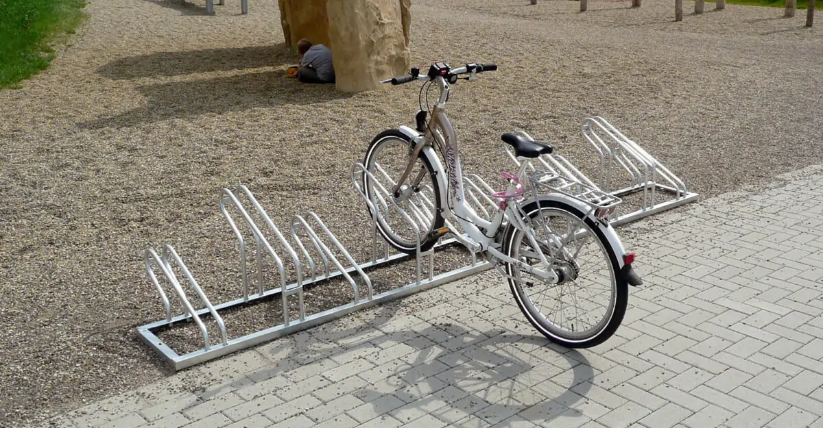 cykel parkeret i en pladsbesparende cykelholder i galvaniseret stål bestående af høje/lave cykelbøjler til parkering af mange cykler