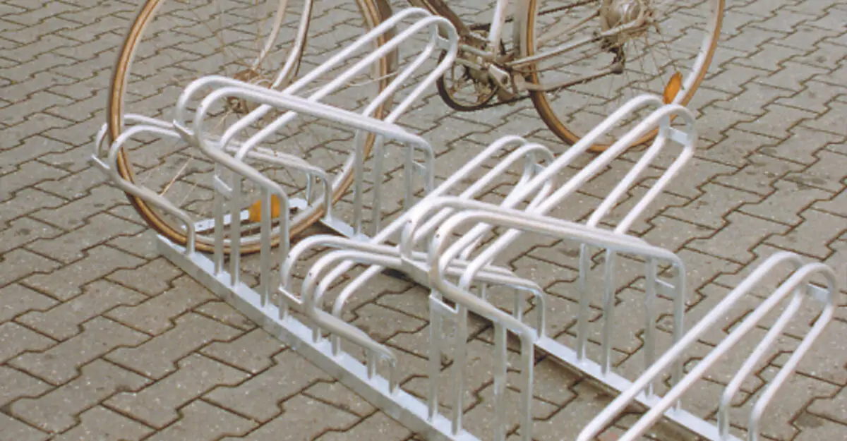 cykel parkeret i en pladsbesparende cykelholder i galvaniseret stål bestående af høje/lave cykelbøjler til parkering af mange cykler