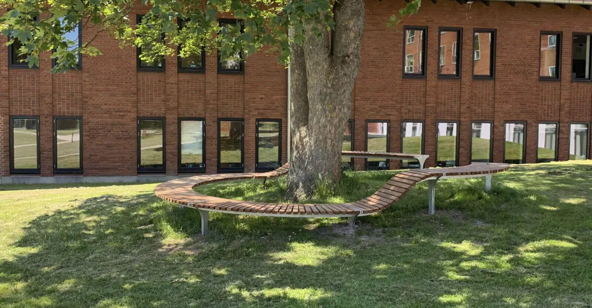 en special bænk i galvaniseret stål og beklædt med mahogni stave rundt om et træ i Odders Vitapark